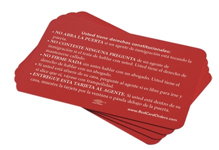 A stack of red cards with Spanish text outlining constitutional rights, advising individuals not to open the door, remain silent, and request a lawyer if approached by immigration agents. The cards also instruct to hand the card to the agent and stay calm.