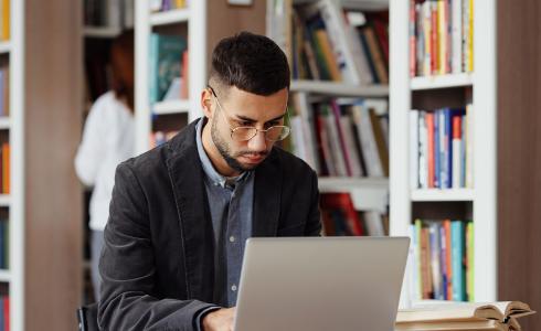 student with laptop in library